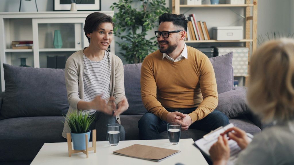 a man and woman sitting on a couch talking to each other